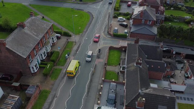 Drone 50fps. Emergency. UK ambulance responder on a street, busy road. 