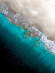 Aerial view of the sea waves rolling into a sandy shore in Western Australia.