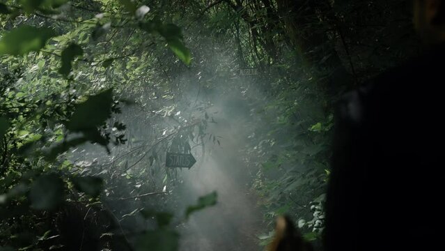 Slow motion back shot of adult man running on a pass in the woods with black signs in the background