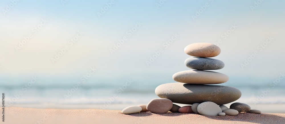 Poster A stack of smooth pebbles resting on the sandy shore with ample copy space in the image
