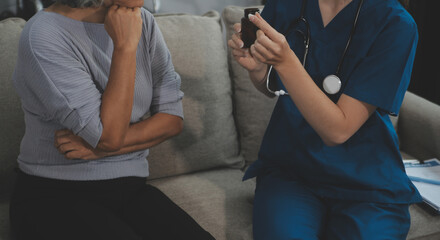 Female caregiver doing regular check-up of senior woman in her home.