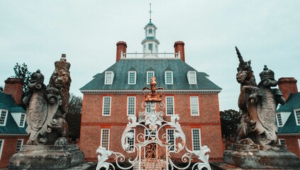 an ornate gate is in front of some buildings with sculptures on the sides, Colonial Williamsburg