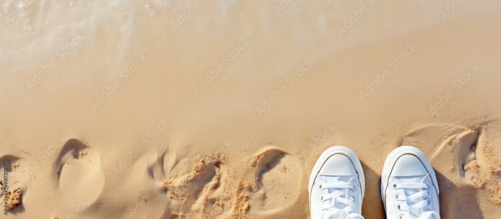 Poster a summer themed selfie of fashionable white sneakers on a sandy beach captured from a top down persp