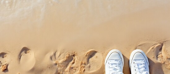 A summer themed selfie of fashionable white sneakers on a sandy beach captured from a top down perspective with additional space for images or text