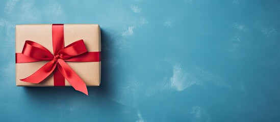 Top view of a gift box with a red bow on a blue background serving as a holiday background Perfect for copy space image