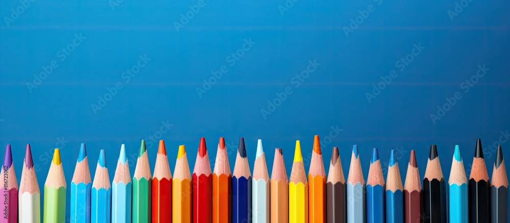 Poster A vibrant arrangement of colored pencils rests on a notebook situated against a backdrop of serene blue The visually striking composition captured in a photograph features a copy space image ideal fo