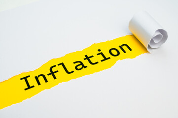 Yellow surface, with the word Inflation in black, underneath torn and rolled white cardboard.
