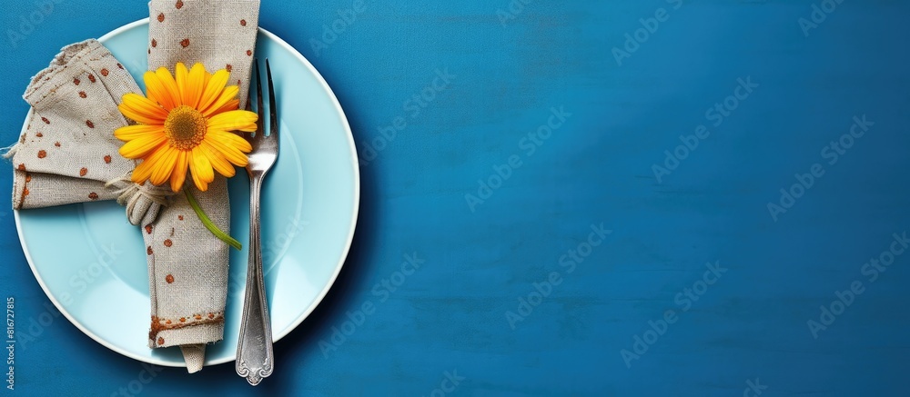 Poster The table is set with silverware a napkin and a flower on a blue background It is a spring themed arrangement seen from above with copy space for an image