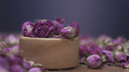 Purple dried rose flower in wooden bowl
