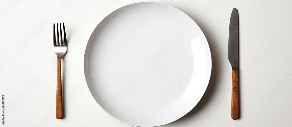 Poster A white plate with a fork and knife placed on a white background leaving empty space for other elements in the image. with copy space image. Place for adding text or design