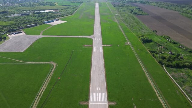 Aerial footage of rural airport runway taxiway and ramp. Airfield tarmac seen from above. Airstrip flyover during a sunny summer day. Instrument landing system on a landing strip. Aerodrome. Bulgaria
