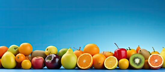 Copy space image of a variety of fruits including orange lemon kiwi and apple set against a vibrant...