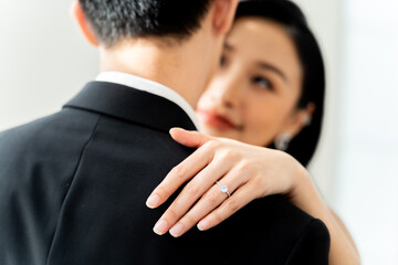 Close-up of groom placing diamond ring on bride's finger, symbolizing eternal love and commitment -...