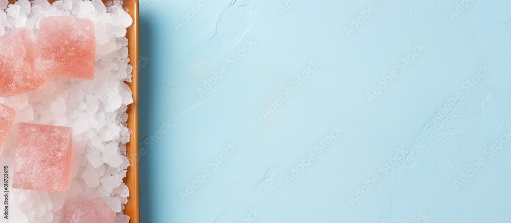 Poster top down flat lay image of a pink himalayan salt plate on a pastel blue background with ample space 