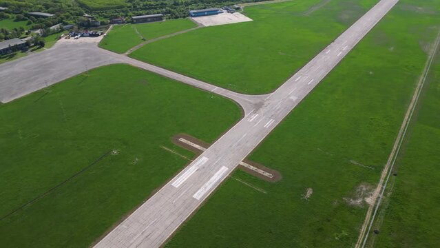 Aerial footage of rural airport runway taxiway and ramp. Airfield tarmac seen from above. Airstrip flyover during a sunny summer day. Instrument landing system on a landing strip. Aerodrome. Bulgaria
