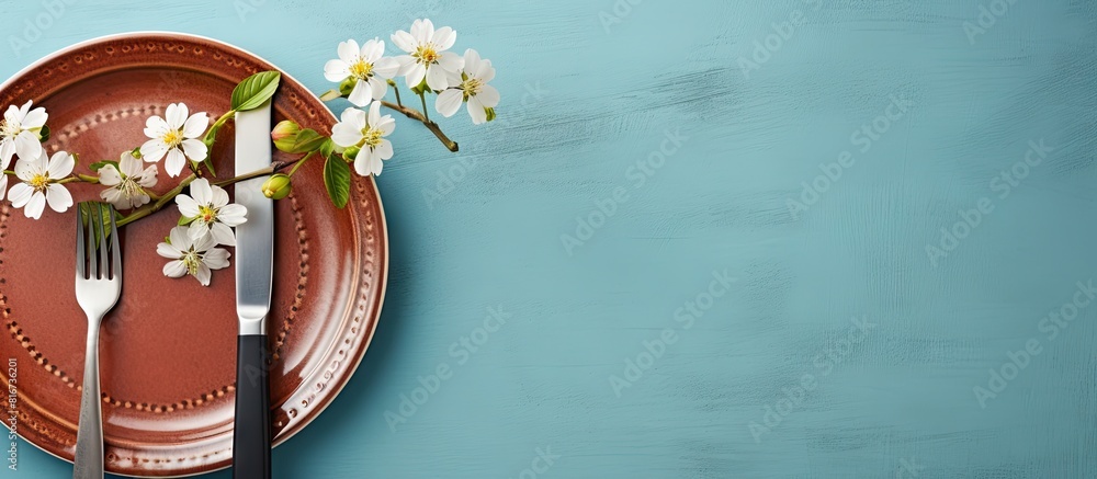Poster The table is set with silverware a napkin and a flower on a blue background It is a spring themed arrangement seen from above with copy space for an image