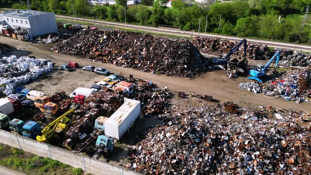 Aerial high angle footage of a recycling plant full of scrap heaps. Shot of metal, paper and plastic garbage separated on piles seen from the air. Scrap yard full of waste materials. Drone shot
