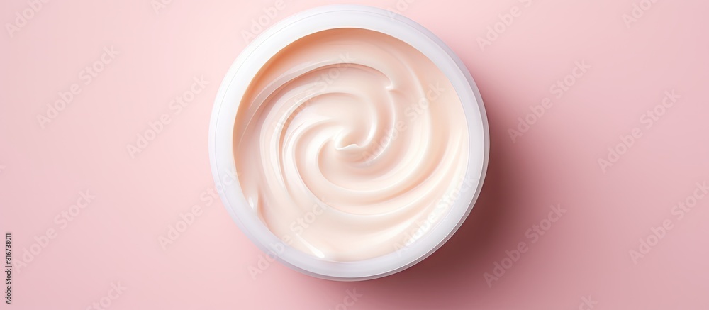 Poster Top view of a moisturizer with a half opened lid placed on a light pink background in a flat lay style with copy space image