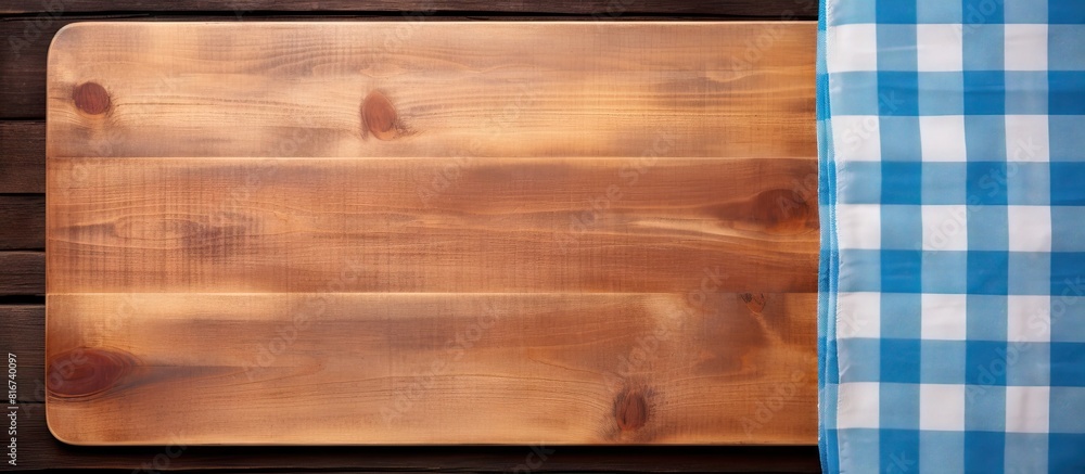 Poster A top down view of a blue table showcasing a wooden cutting board framed by a rustic plaid kitchen tablecloth Ample copy space is available for your text