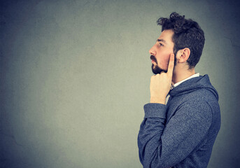 Side profile of a man standing  thinking about question with pensive face expression.