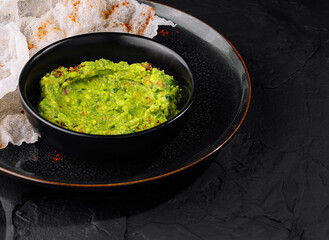 Fresh guacamole with rice chips on dark plate