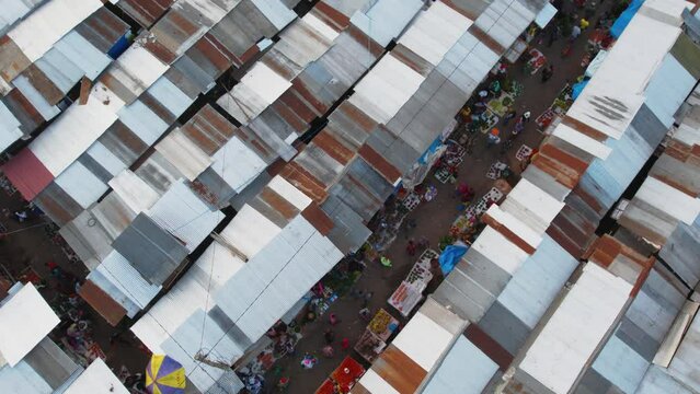 Drone footage of people walking in a narrow road in a local market at sunset in Arusha, Tanzania