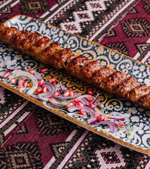 Traditional grilled kebab on ornate plate