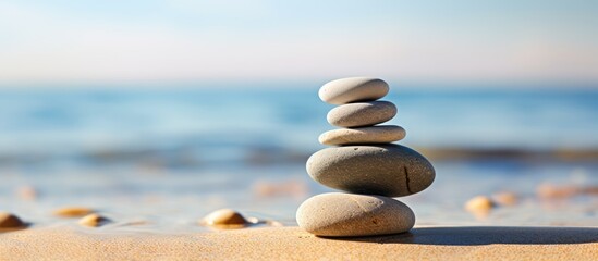 A stack of smooth pebbles resting on the sandy shore with ample copy space in the image
