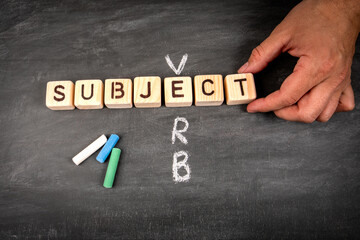 Subject Verb. Wooden block crossword puzzle and pieces of chalk on a chalkboard background