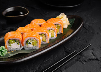 Fresh salmon sushi roll platter on dark background