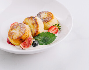 Fresh homemade cottage cheese pancakes with strawberries on white plate