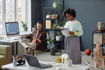 Wide angle view at people working in modern office with Black young woman reading documents in foreground copy space