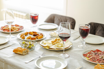 table with food and drinks to eat with friends. Lunch or dinner with succulent portions of cheese, juicy homemade croquettes and tuna tartare and wine in crystal glasses.