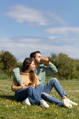Fototapeta premium happy couple in a park watching the sea while drinking coffee in a reusable cup. Happy couple enjoying a sunny day while drinking coffee in a cork glass in a city park.