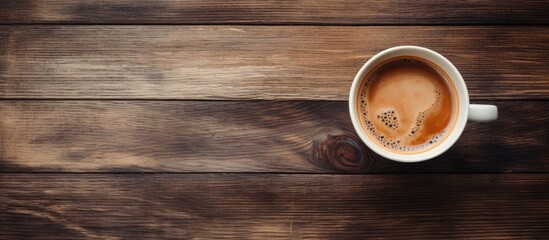 Top view of a cup of coffee on wood background with copy space and texture