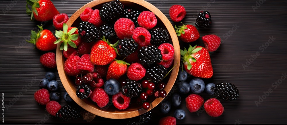 Aufkleber a variety of fresh and ripe berries are displayed in a wooden bowl on a black table with a top down 