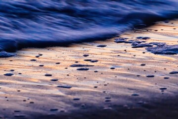a close up of the edge of a sand covered beach