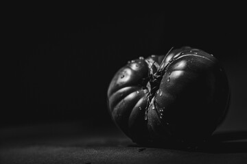 grayscale shot of a ripe Spanish tomato on a solid tabletop, isolated on a blank background