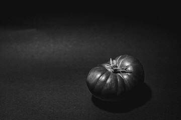 grayscale shot of a ripe Spanish tomato on a solid tabletop, isolated on a blank background