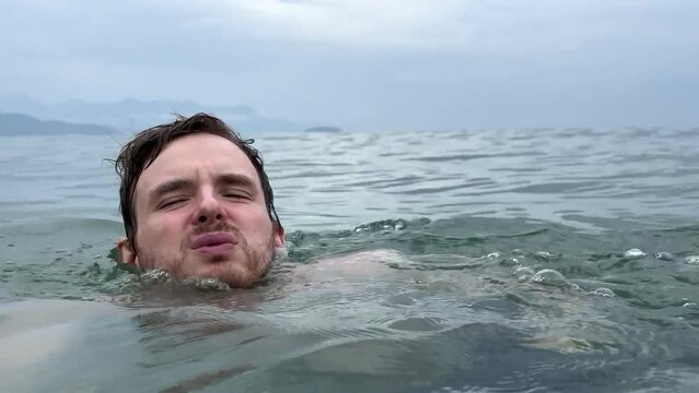 Young scared frightened man having panic attack, drown in water, phobia in the sea