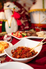 Delicious spicy noodles with meat and vegetables on a red tablecloth in a cafe