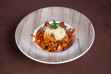 Beef stew with pasta and tomatoes on a plate with cheese topping