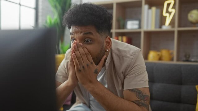 Surprised african american man watching television indoors reacting with different emotions
