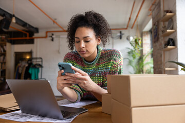 African American female entrepreneur using smartphone to view order details from e-commerce site