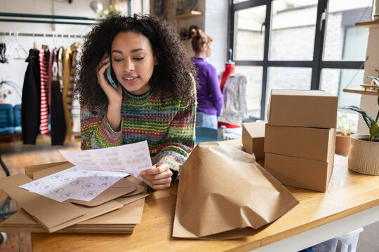 Young female vintage fashion business owner speaking on her smartphone