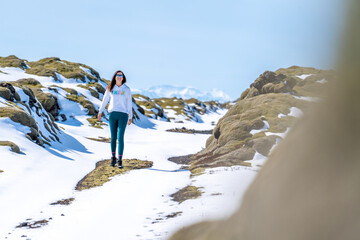 Obraz premium a young girl standing on snow covered ground and rocks and mountains