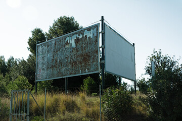 Old billboard with no posters on a lush grassy field