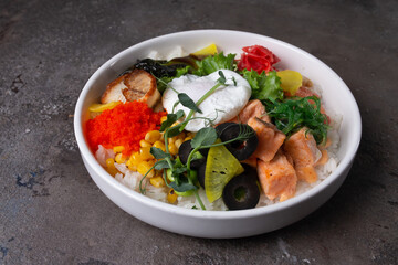 Scrumptious seafood rice bowl with fresh vegetables and egg on a dark background