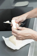 Hands buttering bread near a stovetop, with butter block and knife, in a modern kitchen focus on...