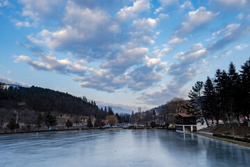 Fototapeta premium Republic of Armenia. Dilijan city. Lake arevik. Dilijan under blue sky. Obelisk of revived Armenia in distance. Traveling around Dilijan. Lake in city park. Holidays in Armenia. Landscape of caucasus